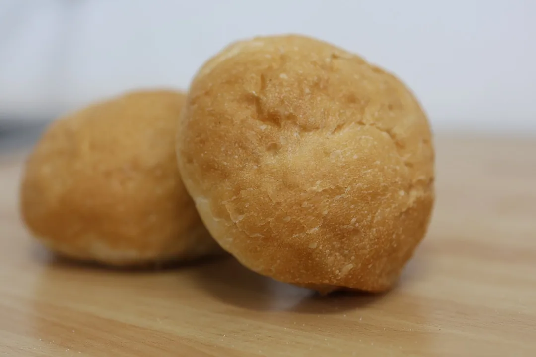 Due buns artigianali dorati su un tagliere di legno