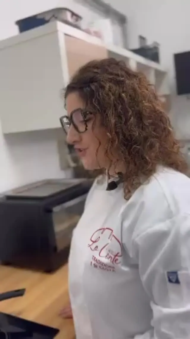 La cuoca di Forno Lo Conte, in giacca bianca, nella cucina dove prepara il panino con hamburger